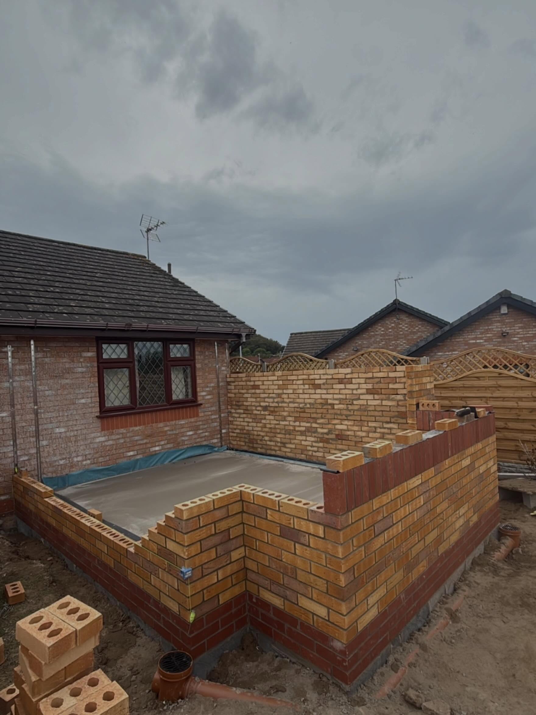 New buff brick garden wall and concrete base built against a bungalow with decorative trellis fencing by DMac Builds