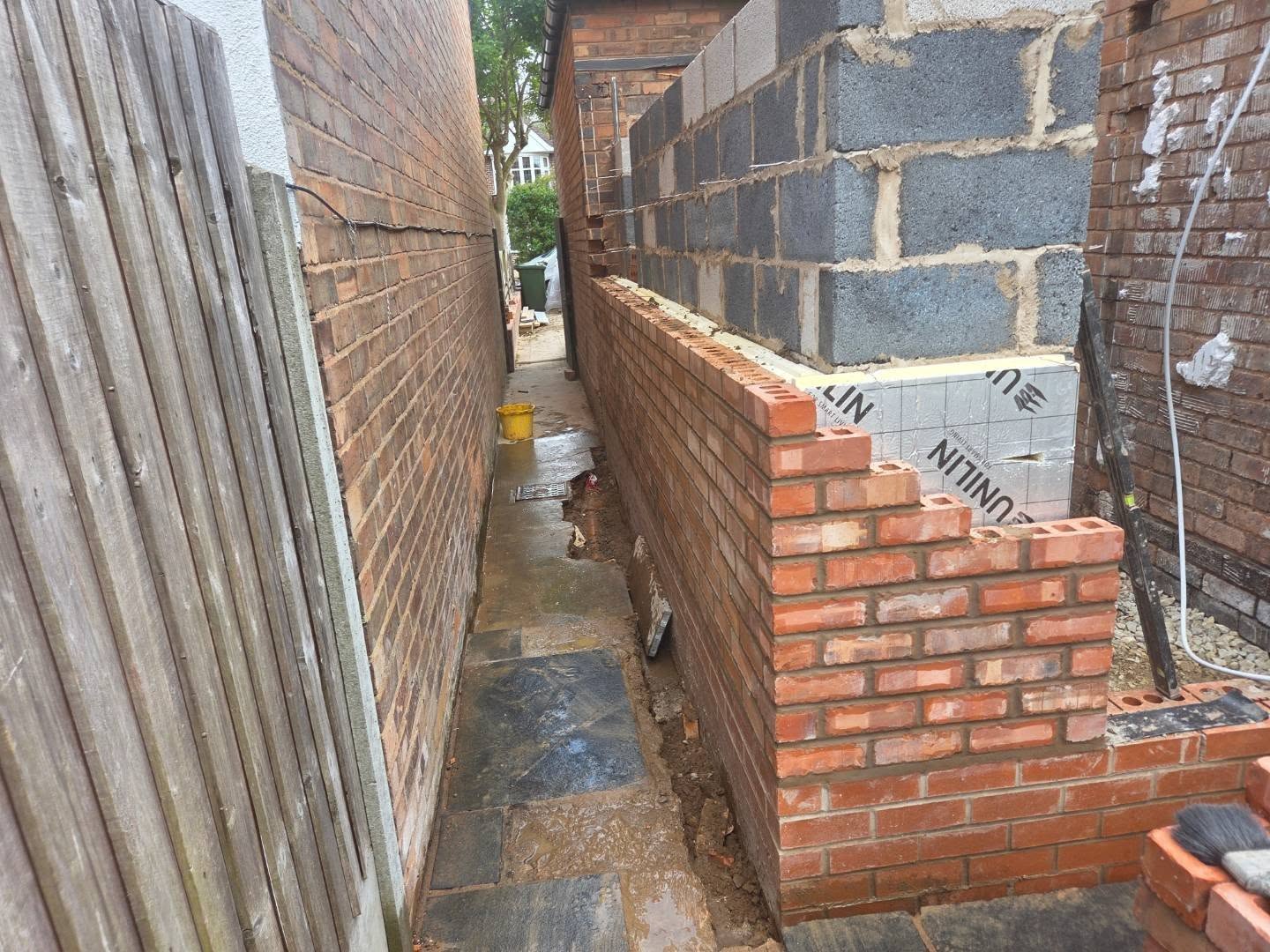 Brick and block side-return wall built between two houses with insulation board as part of an extension by DMac Builds